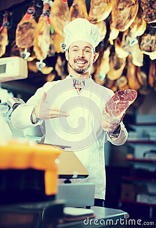 Smiling man butcher showing piece of meat Stock Photo